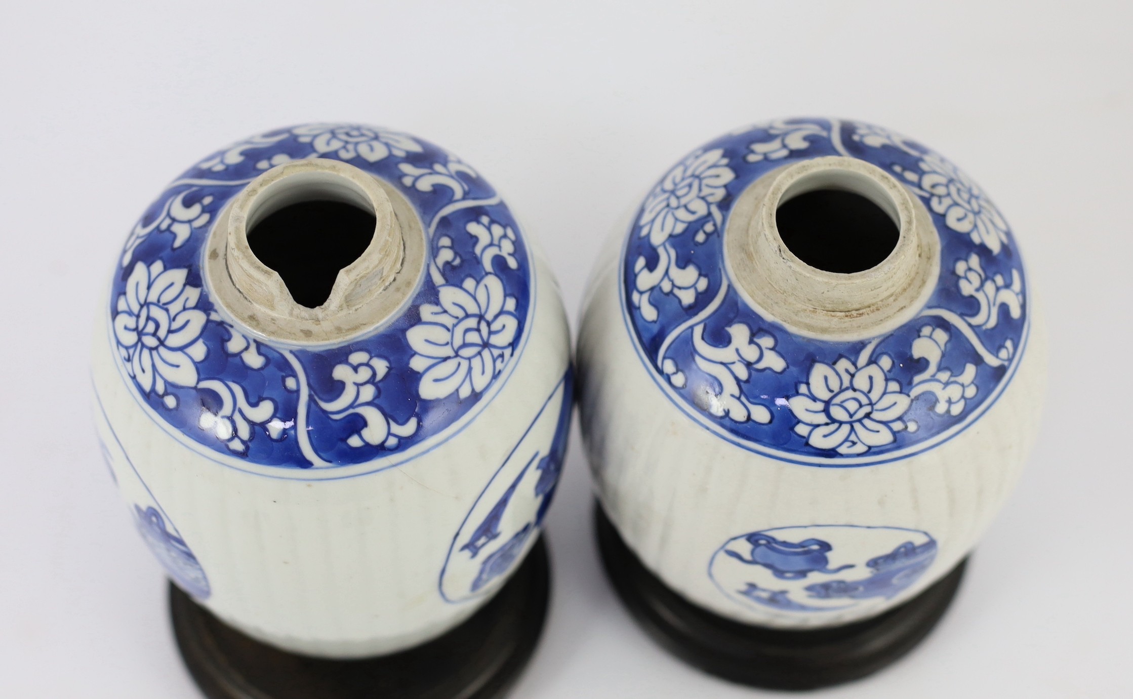 A pair of Chinese blue and white ribbed ovoid jars, Kangxi period, 13.4cm high, excluding wood stand and cover, one chipped with hairline crack
